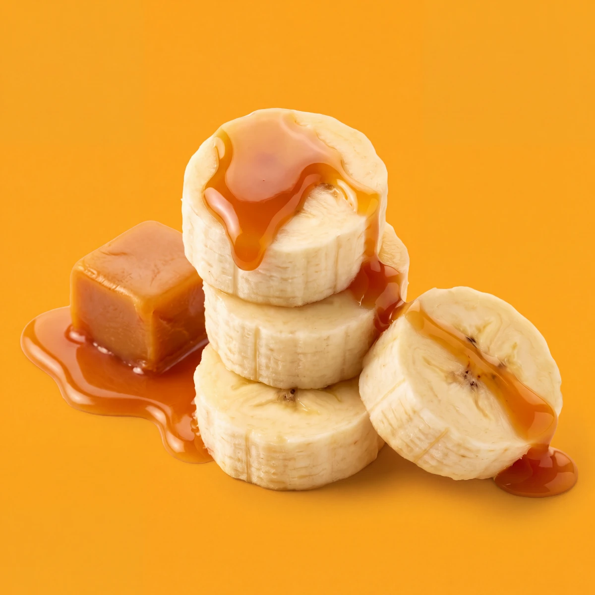 Banana slices with caramel drizzle and a caramel cube on an amber backdrop