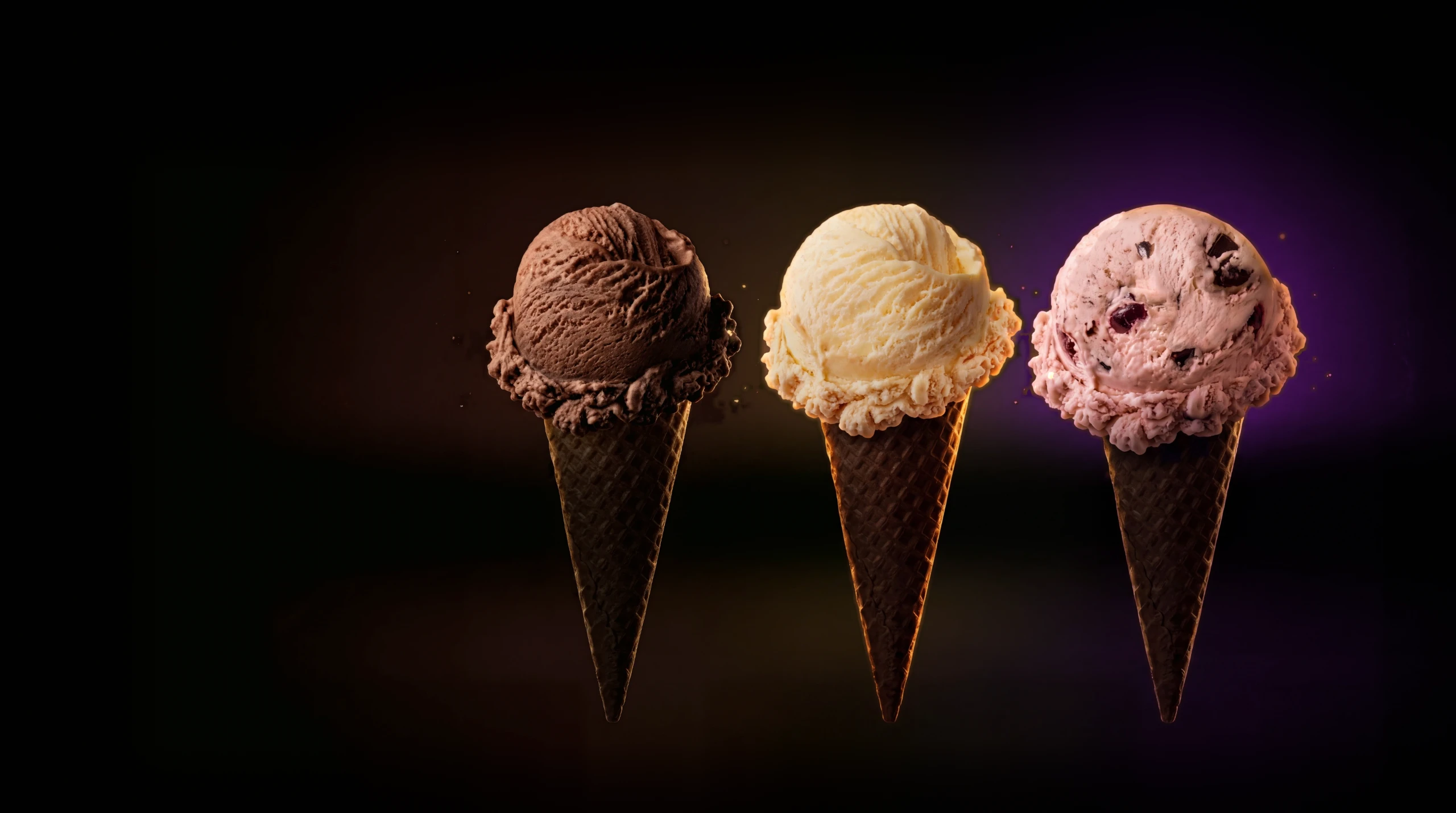 Chocolate, vanilla and cherry chocolate ice cream cones, each lit with its own coloured glow