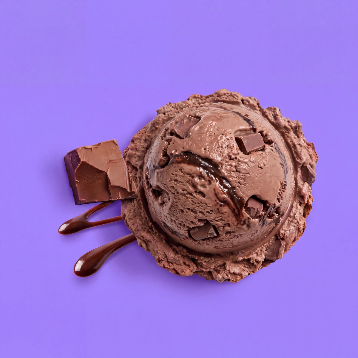 Top-down scoop of triple chocolate ice cream with chocolate sauce on a violet backdrop