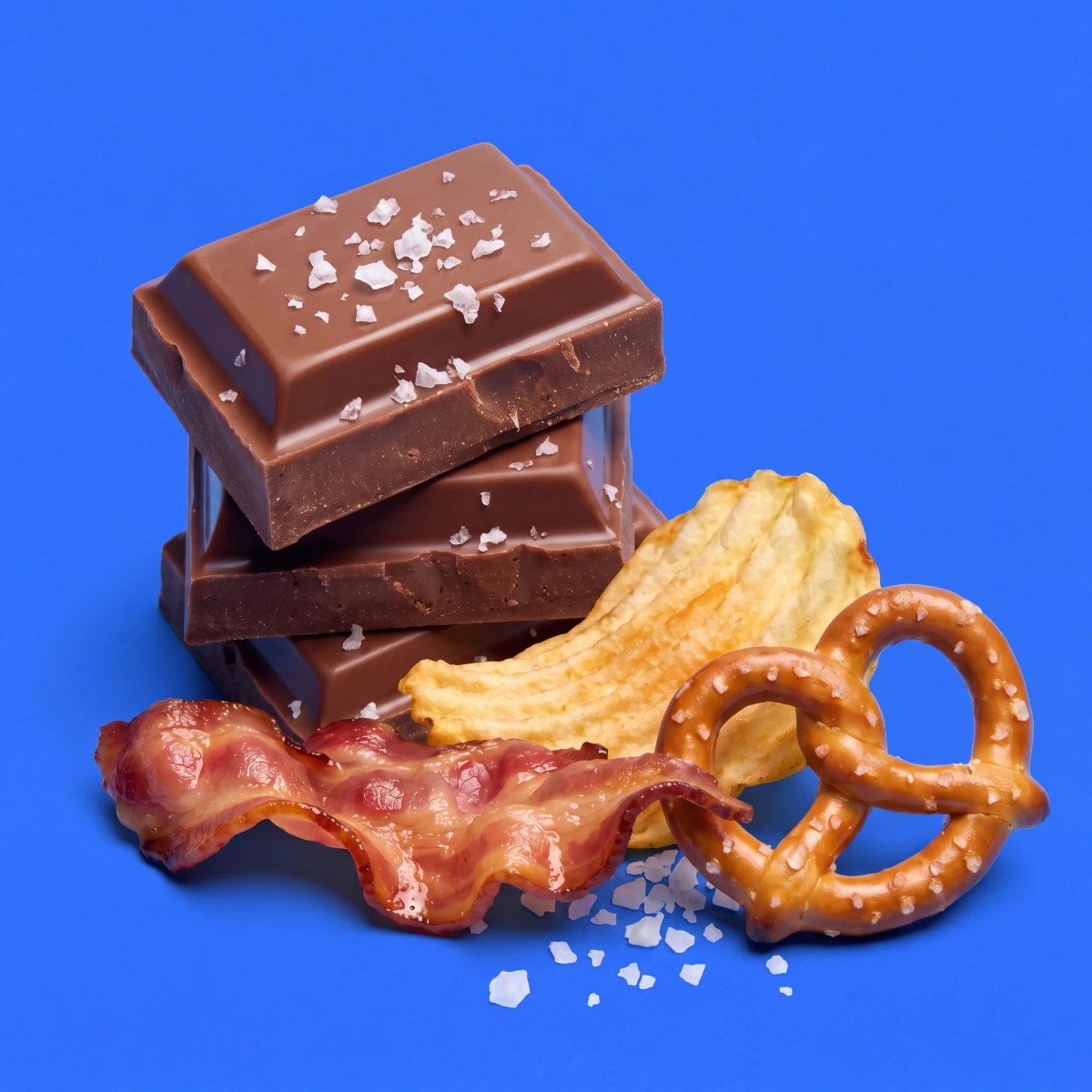 Sea-salted milk chocolate with pretzel, potato chip and bacon on a cobalt-blue backdrop