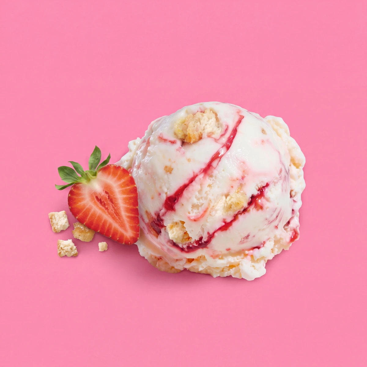 Top-down scoop of strawberry cheesecake ice cream with a half strawberry on a pink backdrop