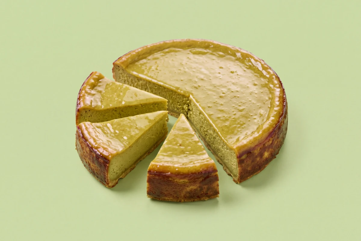 Pistachio cheesecake with cut slices on a pistachio-green backdrop